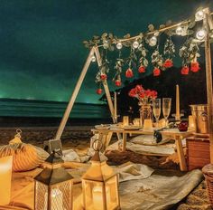 an outdoor setting with candles and flowers on the beach