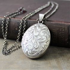 "This extra large sterling silver locket has a lovely swirling plume design etched on the front. The back of the piece, which has been engraved with the previous owners initials MEW, bears the traditional English hallmarks, made in Birmingham England in 1977. Opening reveals two spaces in which to place your beloved photographs.. The pendant is set on a new long sterling silver chain which has been antiqued to a rich charcoal gray. The chain has a little surprise at the end, tiny garnet stones f Vintage Carved White Gold Jewelry, Ornate Antique Silver Carved Jewelry, Vintage Silver Carved Jewelry, Vintage Carved Silver Jewelry, Ornate Carved White Gold Jewelry, Victorian Carved Silver Jewelry, Victorian Style Carved Silver Jewelry, Sterling Silver Locket Necklace For Vintage Collection, Vintage White Gold Jewelry With Engraving Option