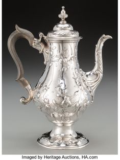 an ornate silver tea pot with a handle on the top and handles to the sides