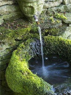 a water fountain with moss growing on the sides and flowing from it to the ground