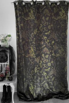 a shower curtain with skulls on it next to a white shelf and black booties