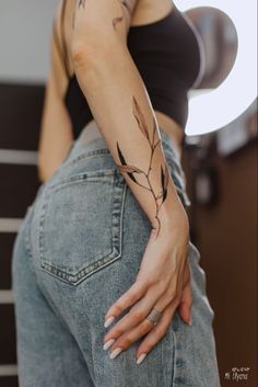 a woman with a tattoo on her arm holding onto the back of her pants,