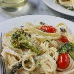 pasta with broccoli and tomatoes on a white plate