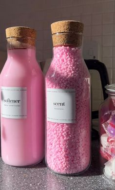 two jars filled with pink candy sitting on top of a counter next to each other