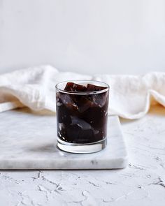 a glass filled with ice sitting on top of a white countertop next to a napkin