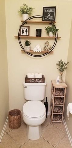 a white toilet sitting inside of a bathroom next to a shelf filled with potted plants