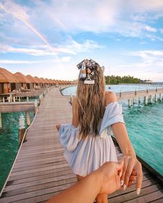 a woman holding the hand of a man on a pier