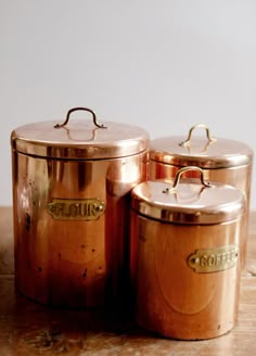 three copper pots sitting on top of a wooden table