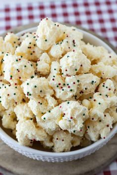 a white bowl filled with popcorn and sprinkles on top of a checkered table