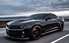 a black chevrolet camaro driving down the road