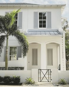 a white house with shutters and palm trees