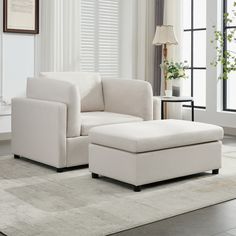 a living room with a white couch and footstool in front of a window