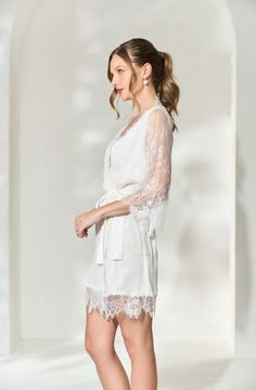 Made in a unique delicate white french lace design, the Lara Lace Robe is the perfect gift for the bride-to-be on her wedding day. Featuring scalloped lace edges along the neckline, hem and sleeve cuffs, this robe exudes old-world elegance. The body of the Lara Robe is fully lined to provide our brides the coverage they need. A slip dress is not required for under this robe, but if you're in search of one we recommend our White Bridal Slip Dress. Material: French lace with a fully lined bodySlee White Feminine Lace Top With Lace Trim, Elegant Lace Dress With Scalloped Lace For Wedding Night, Elegant Scalloped Lace Dress For Wedding Night, White Lace Bridesmaid Dress With Scalloped Lace, White Scalloped Lace Dress For Bridesmaid, Long Sleeve Lace Wedding Dress With Lace Cuffs, White Lace Dress With Lace Sleeves For Bridesmaid, Elegant Lace Wedding Dress With Lace Cuffs, White Lace Dress For Bridal Shower