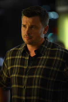 a man in a plaid shirt looking at the camera with his hand on his hip