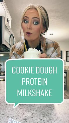 a woman holding a cup with the words cookie dough protein milkshake on it