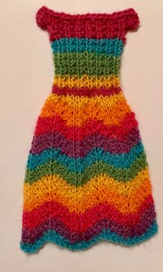 a multicolored knitted dress is displayed on a white surface