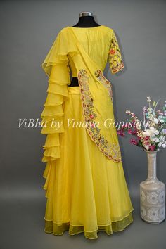 The Yellow Lehenga combines traditional elements with modern design. The beautifully embroidered blouse adds a touch of elegance, while the detachable draped saree dupatta offers versatility and convenience. With delicate ruffles along the end, this lehenga is perfect for any special occasion and Haldi events.. Organza Blouse With Cutdana For Reception, Organza Blouse Piece For Reception, Floral Embroidered Pre-draped Saree For Party, Transitional Organza Blouse Piece For Reception, Transitional Georgette Lehenga With Floral Embroidery, Traditional Drape Organza Blouse With Cutdana, Diwali Blouse In Organza With Traditional Drape, Traditional Drape Organza Blouse For Diwali, Diwali Organza Blouse With Traditional Drape