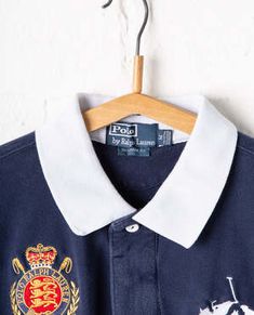 Casual Navy Polo Shirt With Embroidered Logo, Navy Polo Shirt With Embroidered Logo, Classic Top With Collared Neckline And Embroidered Logo, Classic Top With Embroidered Logo And Collared Neckline, Classic Navy Polo Shirt With Ribbed Collar, Collared Polo Shirt With Embroidered Logo, Collared Polo Shirt With Embroidered Logo For Work, Classic Blue Polo Shirt With Embroidered Logo, Navy Top With Embroidered Logo For College