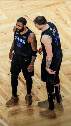 two basketball players standing in the middle of a court talking to each other with their hands on their hips