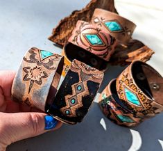 a person holding several bracelets with designs on them