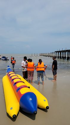 several people in life jackets standing on the beach next to an inflatable boat