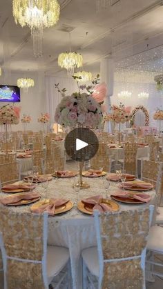 a table set up for an event with flowers and plates on it, surrounded by chandeliers