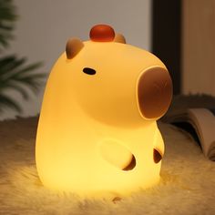 a yellow light shaped like a pig sitting on top of a rug next to a book