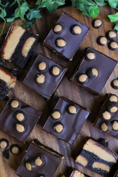 several pieces of chocolate and peanut butter cake on a wooden cutting board with green leaves in the background