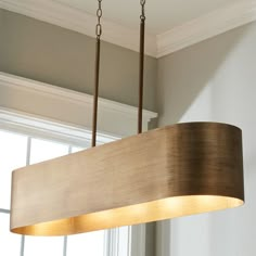 a wooden light fixture hanging from a ceiling in a room with white walls and windows