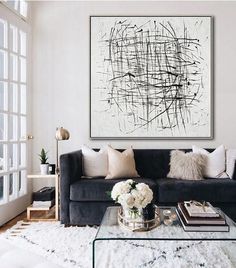 a living room with a couch, coffee table and large painting on the wall above it