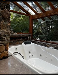 a large jacuzzi tub sitting under a window next to a stone wall and fireplace