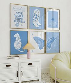 a living room with four blue and white prints on the wall next to a yellow chair