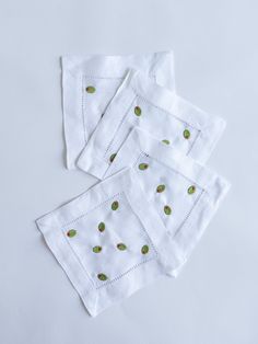 four white napkins with green leaves on them