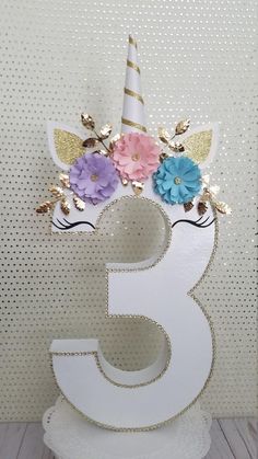 the number three is decorated with flowers and a unicorn's head on top of it