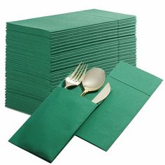 a stack of green napkins with gold forks and spoons sitting on top of them