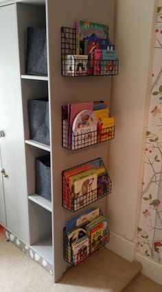 a book shelf filled with lots of books next to a wall covered in pictures and toys