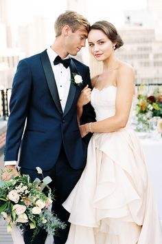 a bride and groom standing on the beach