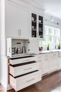 a kitchen with white cabinets and wooden floors