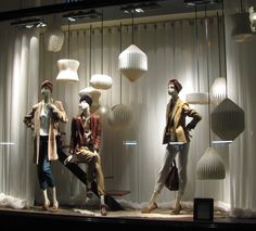 three mannequins are sitting in front of white curtains and hanging light bulbs