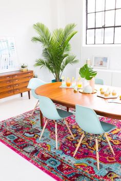 a dining room table with blue chairs and a rug