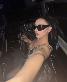 a woman in sunglasses is sitting on a bus