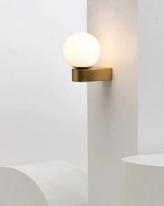 a light that is on the side of a white wall next to a round object