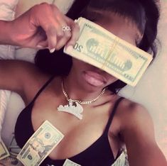 a woman holding money in her hand and covering her eyes with one hundred dollar bills