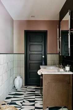 a bathroom with black and white tile flooring next to a sink in the corner