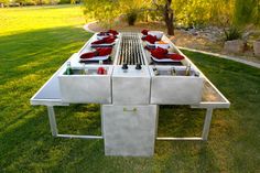 a long table made out of cinder blocks in the middle of a field with red pillows on it