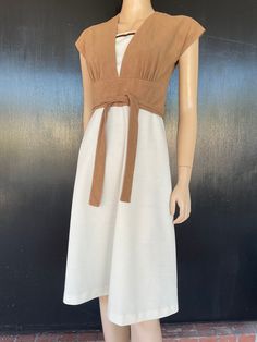 "1970s Jerell of Texas dress. Beige doe skin texture polyester bodice with cream polyester skirt . Panel in bodice matches skirt and has knit trim in shades of brown. Attached tie belts on sides wrap around to tie in front or back. Nylon zip back. Measurements are  34\" bust 26\" waist 36\" hips 16\" bodice length  42\" length Cute dress shows well, exhibiting minimal wear. Small dark (ink?) spot noted on skirt back by zipper edge as shown in pics." Retro Beige V-neck Dress, Beige V-neck Retro Dress, Vintage Beige V-neck Midi Dress, Brown Fitted Dress With Tie Waist, Fitted Brown Dress With Tie Waist, Retro Brown V-neck Dress, Texas Dress, Tie Belts, White And Silver Dress