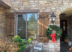 the front door of a stone house with wreaths on it