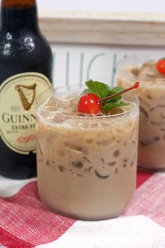 two glasses filled with ice cream and topped with cherries next to a bottle of guinness