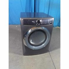 a black and silver washer sitting in front of a blue curtain