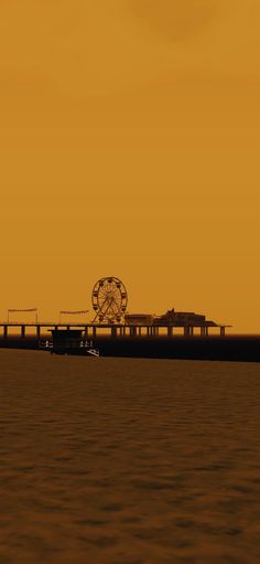 a large long pier with a ferris wheel on it's end and an orange sky in the background